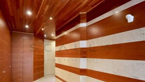 A hallway with wooden paneling and marble accents, leading to a door with a logo. - LUXURY LISBOA APARTMENT T2 (Lisbon)