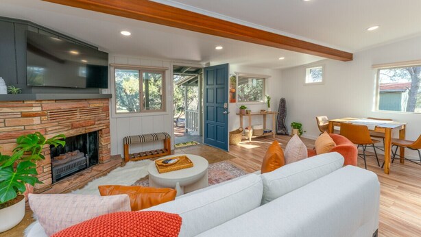 A spacious living room with a fireplace, a large sofa, and a dining area with a table and chairs. - Guest House @ Juniper Ranch | Private, Views, King (Sedona)