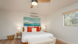 A bedroom with a bed, a ceiling fan, an air conditioner, a window with a view, and a painting on the wall. - Guest House @ Juniper Ranch | Private, Views, King (Sedona)
