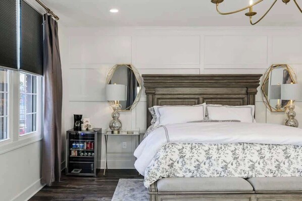 Une chambre à coucher avec un grand lit, des lampes de chevet, une table de chevet, une machine à café et une étagère contenant divers objets.
