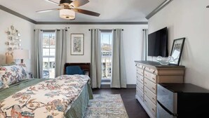 Un dormitorio con cama, cómoda, televisor y ventilador de techo.