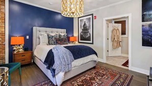 Un dormitorio con una cama grande, dos lámparas de noche, un tapete estampado y un candelabro.