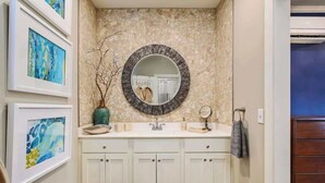 Un baño con pared de piedra, un espejo redondo, un lavabo y armarios.