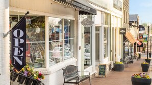 Une devanture de magasin avec une enseigne « OUVERT », un banc à l’extérieur et des plantes en pot sur le trottoir.
