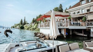 A waterfront restaurant with outdoor seating, boats docked nearby, and a view of the water.
