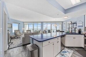 Une cuisine moderne dotée d’un grand îlot central, un coin repas offrant une vue agréable et un salon avec vue.
