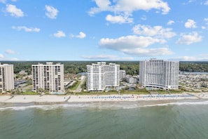 Um complexo hoteleiro à beira-mar, com vários edifícios altos, orla e área de piscina.