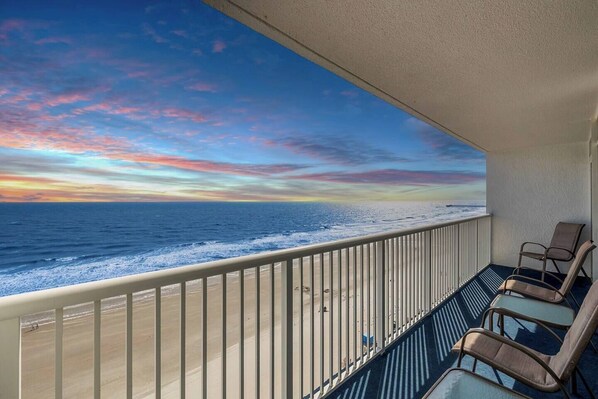 A balcony with a view of the ocean, equipped with lounge chairs.
