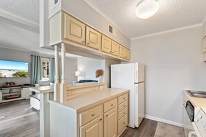 A compact kitchen with a built-in refrigerator, a dining area with a view, and a TV mounted on the wall.