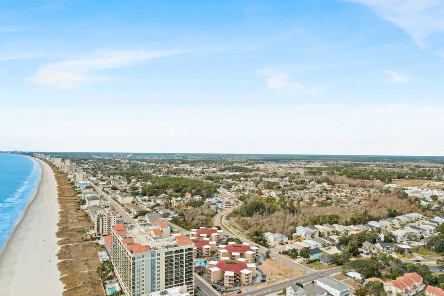 A coastal cityscape with a beachfront hotel, residential areas, and a mix of commercial buildings.