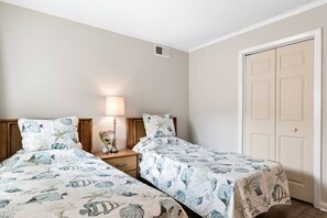 A bedroom with two beds, a nightstand with a lamp, and a door. - Pools - Near Main St - Beach Steps Away - Waipani (North Myrtle Beach)