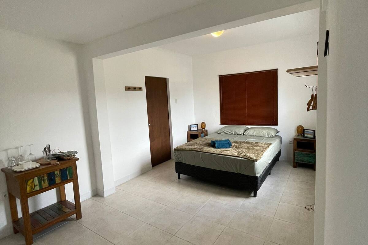 A spacious bedroom with a large bed, a bedside table, and a wardrobe.