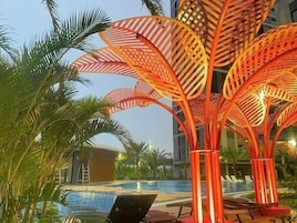 Uma área de piscina com design moderno, incluindo uma estrutura em formato de folha e espreguiçadeiras.