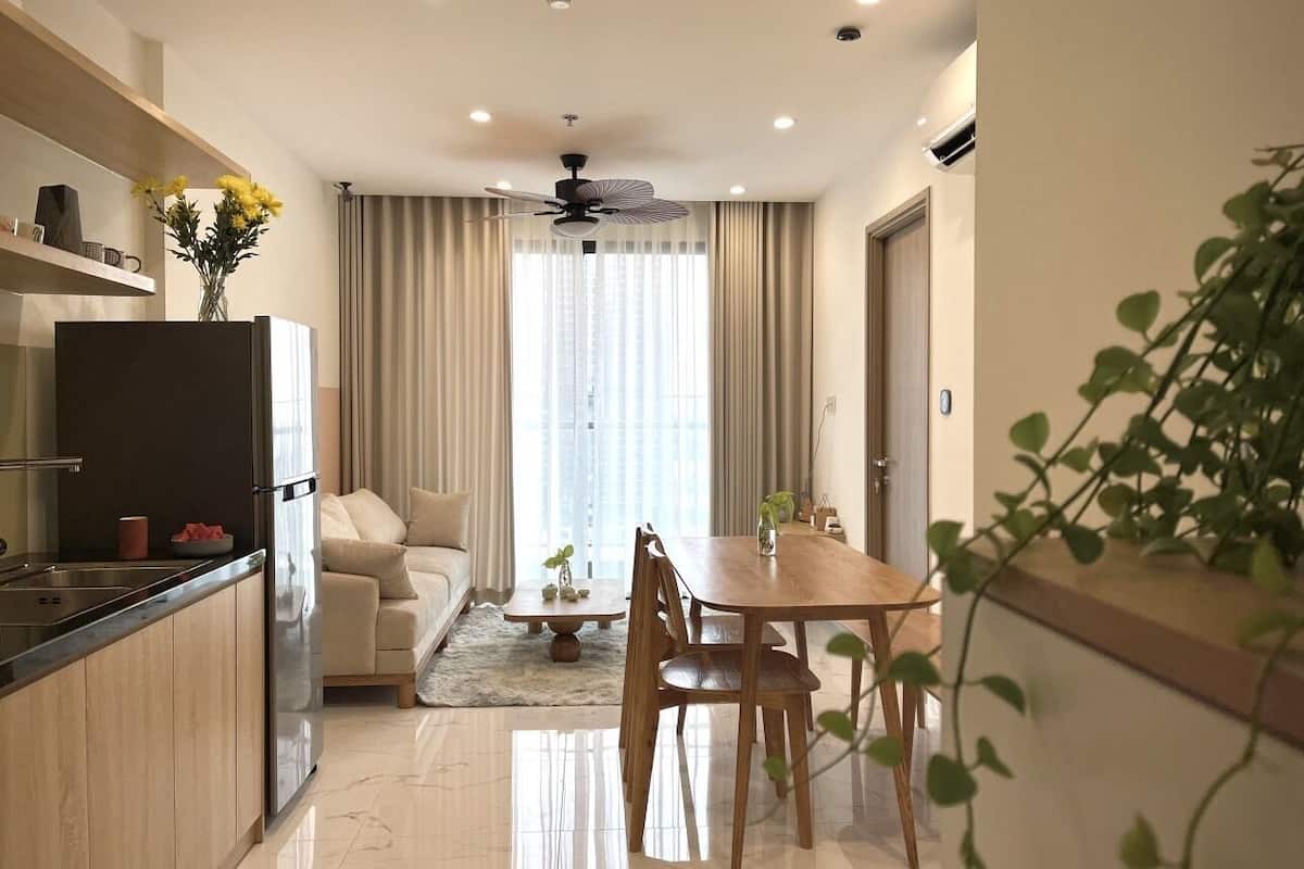 Une cuisine moderne avec un coin repas, un ventilateur de plafond et une vue sur le salon par une fenêtre.