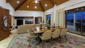 Un vaste espace de vie doté d’un haut plafond, d’une table à manger pouvant accueillir six personnes et d’une grande fenêtre offrant une vue sur l’extérieur.