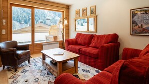 Un salon chaleureux avec un canapé rouge, une table basse en bois et un fauteuil en cuir.