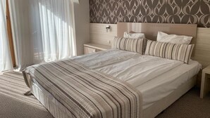 A bedroom with a large bed, a bedside table, and a headboard with a patterned wallpaper. - Stayinn Granat - 2 Bedroom Apartment - Next to Gondola Lift, Perfect for 4pers (Bansko)
