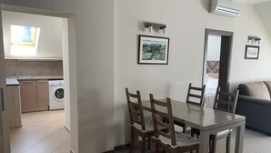 A dining area with a table and chairs, a kitchen in the background, and a living room with a sofa. - Stayinn Granat - 2 Bedroom Apartment - Next to Gondola Lift, Perfect for 4pers (Bansko)