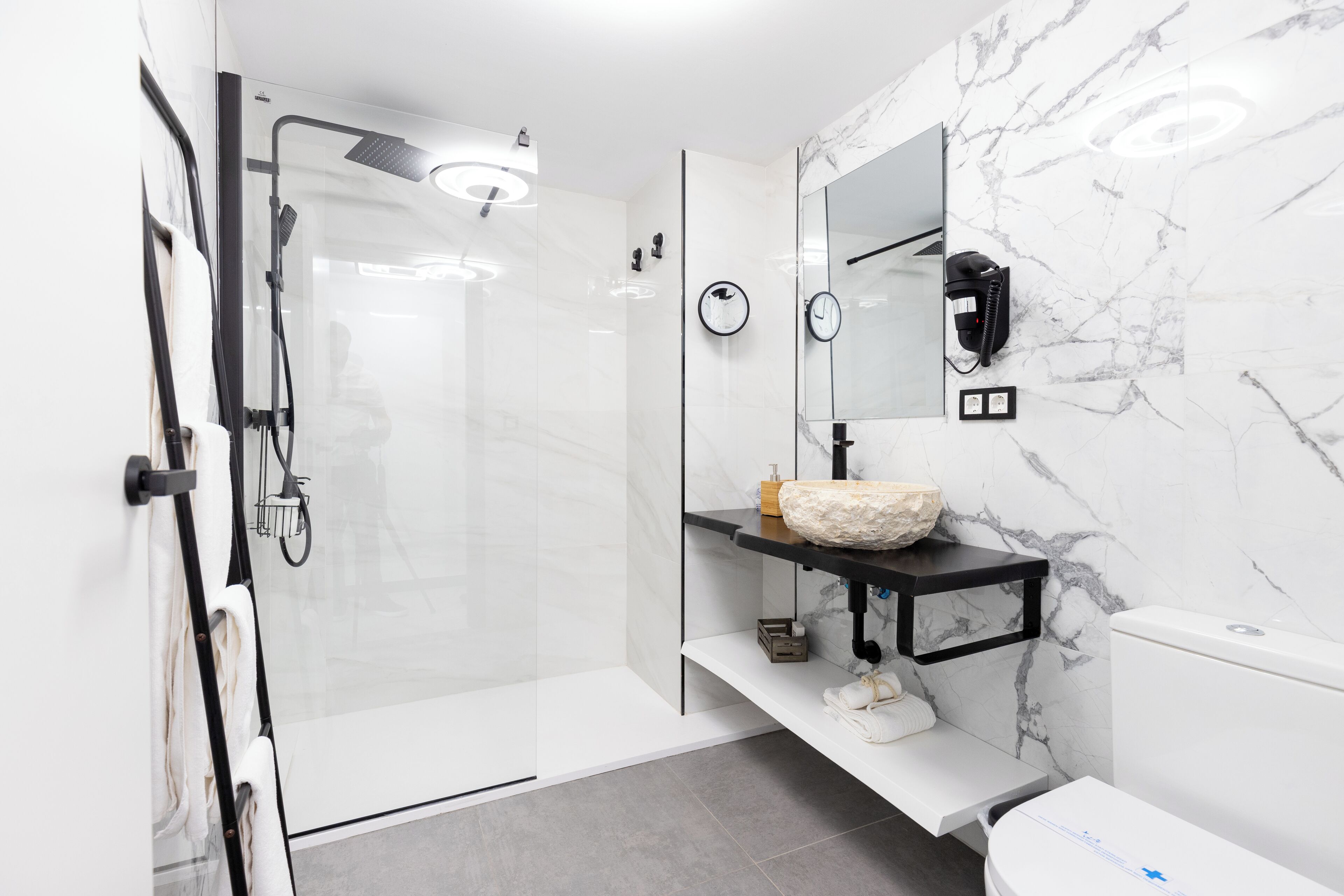 A modern bathroom with a glass-enclosed shower, a marble sink, and a toilet.