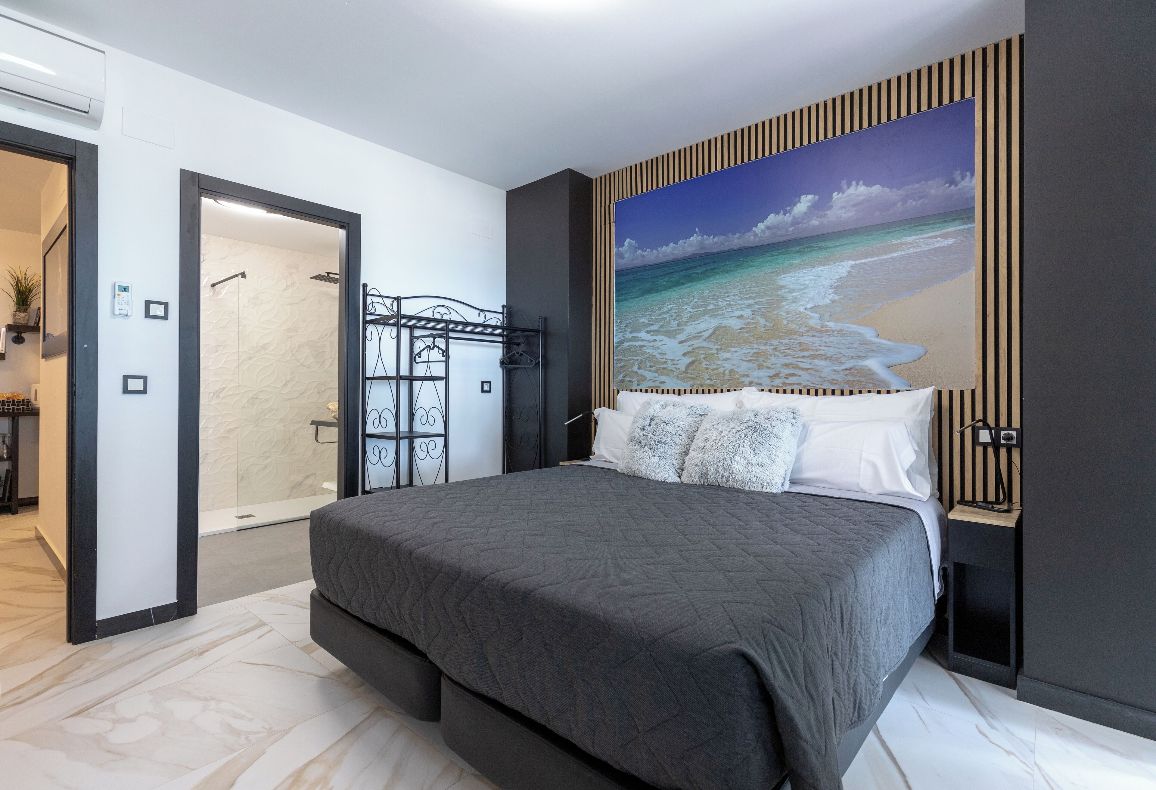 Quarto moderno com uma cama grande, um quadro de uma praia e um closet espaçoso.
