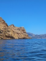 A coastal landscape with rocky cliffs and a clear blue sea.