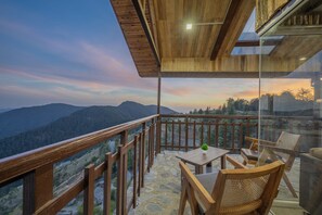 A wooden deck with a table and chairs, overlooking a mountainous landscape. - Hotel Wood Winds by Eastlynn Experiences, Chail (Shimla)