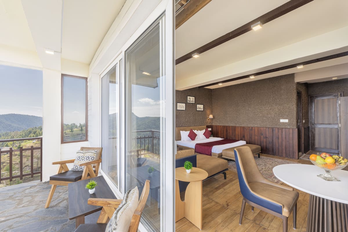 A modern hotel room with a balcony, a cozy seating area, and a dining table.