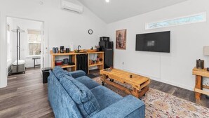 Un saló amb un sofà, una taula de centre, un televisor i una zona de cuina amb un frigorífic i un microones.