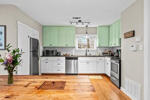 A kitchen with white cabinets, a stainless steel refrigerator, a dishwasher, a microwave, and a stove.