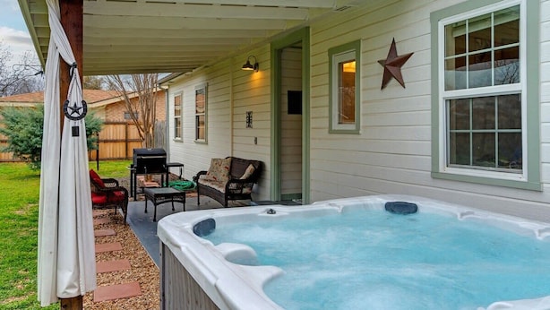 Une terrasse couverte avec un jacuzzi, du mobilier d’extérieur et une décoration en forme d’étoile sur le mur.