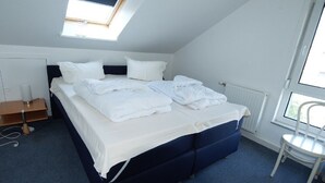 A bedroom with a bed, a chair, a desk, and a window.