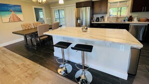 Una cocina moderna con una isla central, taburetes de bar e iluminación colgante.