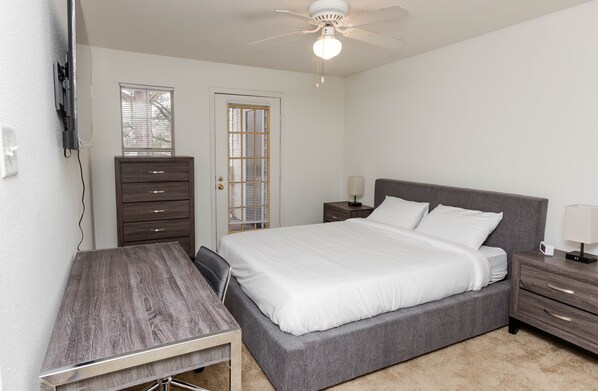 A bedroom with a bed, a desk, a dresser, and a nightstand.
