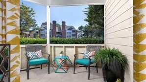 A covered outdoor seating area with two chairs and a small table, surrounded by decorative vases and a potted plant. - City Chic: 1BR Gem Perfect for Couple (Hampton)