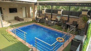 Uma área de piscina no terraço com piscina, espreguiçadeiras e espaço para churrasco.