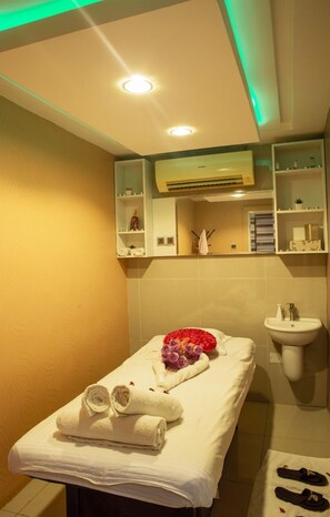 A small, well-lit room with a single bed, a sink, and a mirror above it.