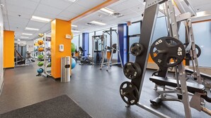 Een sportschool met diverse fitnessapparaten, waaronder krachttoestellen en losse gewichten.