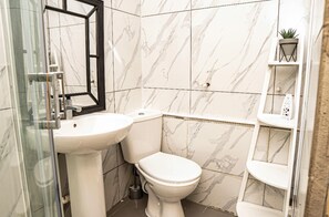 Un bagno con lavandino bianco, WC e piastrelle in marmo.