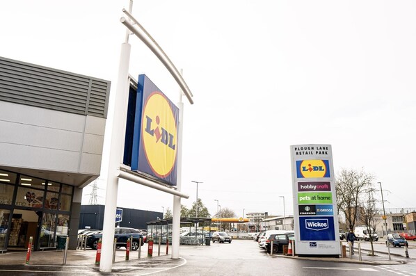 A Lidl store with a large sign and a signboard listing nearby amenities like hobbycraft, pets at home, Starbucks, Greggs, and Wicks. - Luxury Studio Flat in London (London)