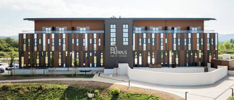 A modern hotel with a flat roof, large windows, and a landscaped entrance area.
