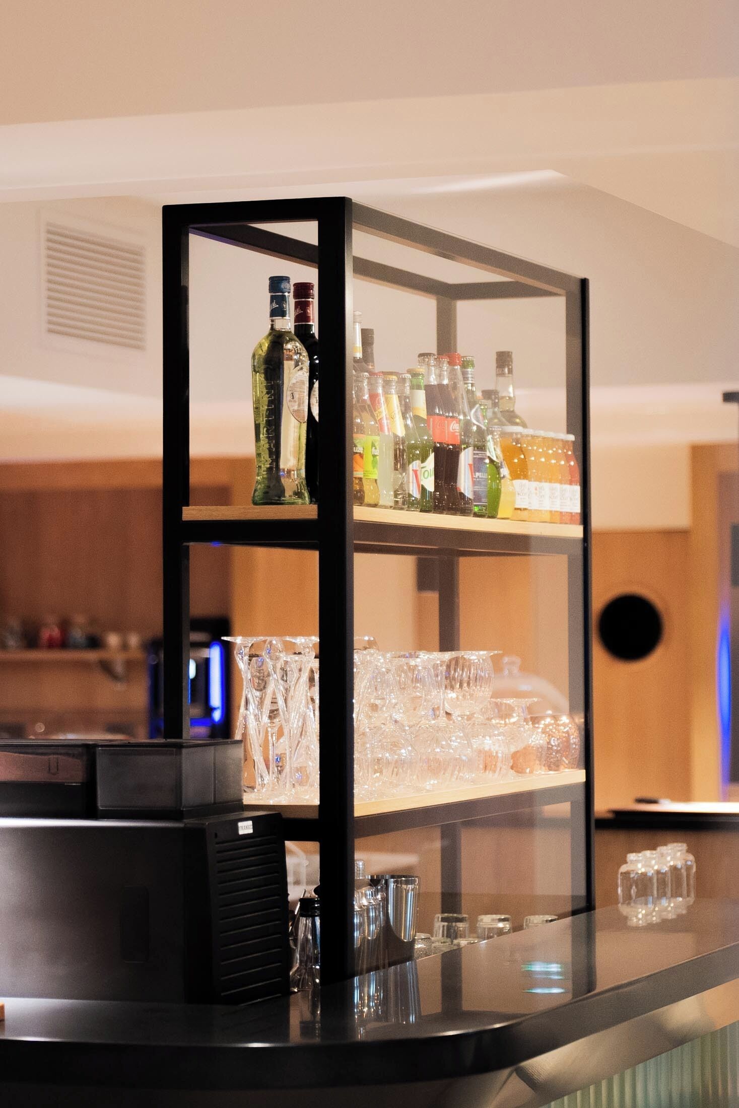 Un espace bar avec des étagères remplies de bouteilles et de verres.
