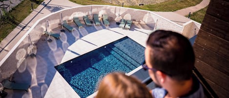 A rooftop pool area with lounge chairs and a view of the surrounding landscape.