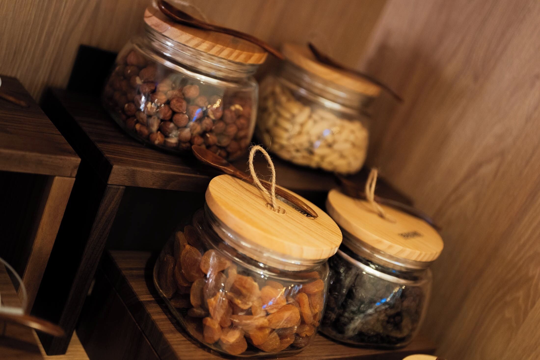A wooden shelf with three glass jars containing different food items.