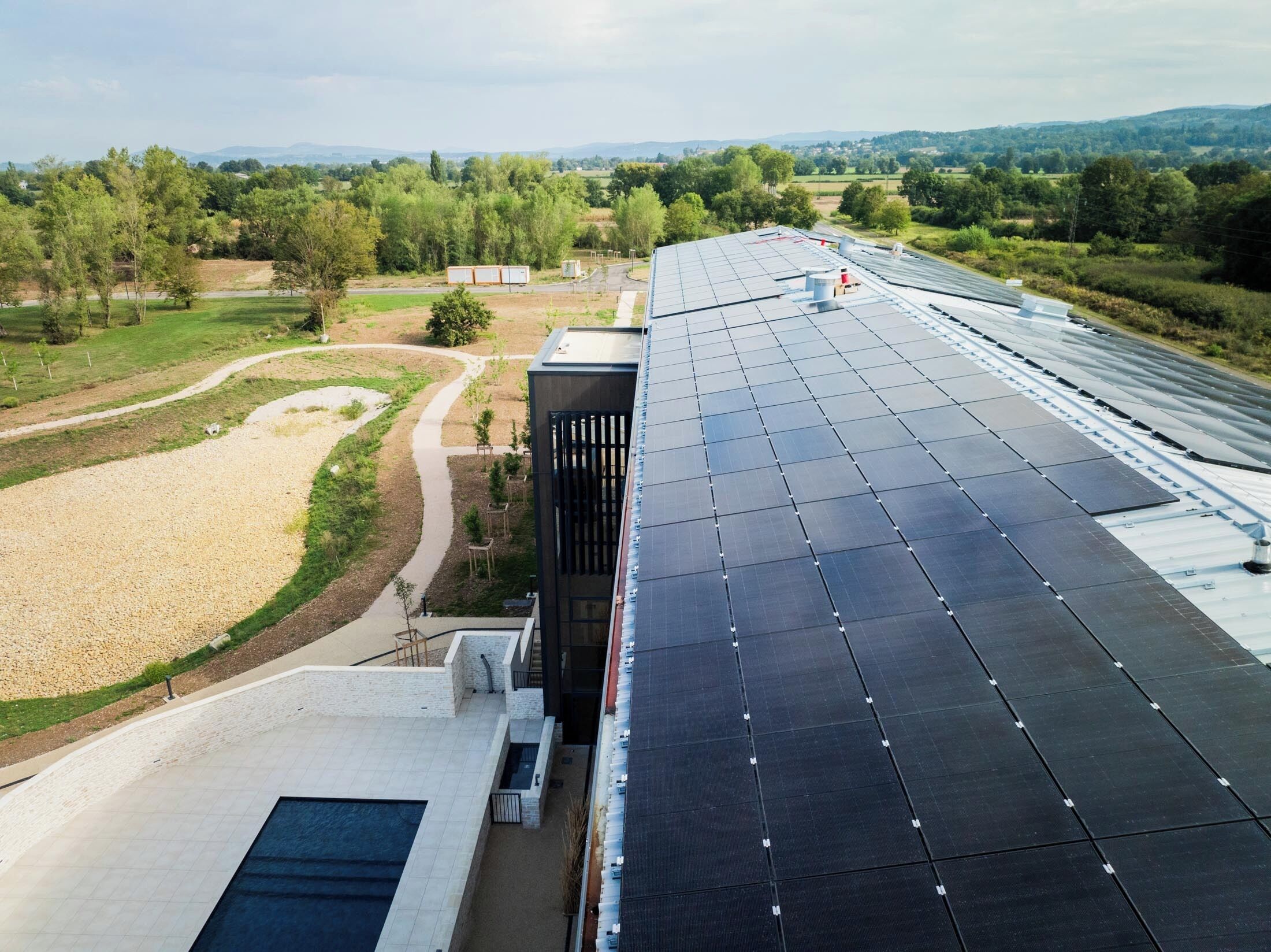 A modern building with a rooftop solar panel array and a swimming pool.