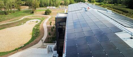 A modern building with a rooftop solar panel array and a swimming pool.