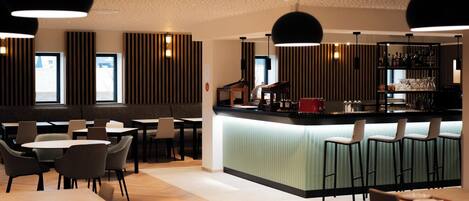 A modern bar area with a counter, stools, and a variety of bar tools.