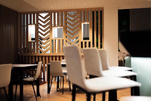 Un comedor moderno con separadores de madera y sillas blancas.