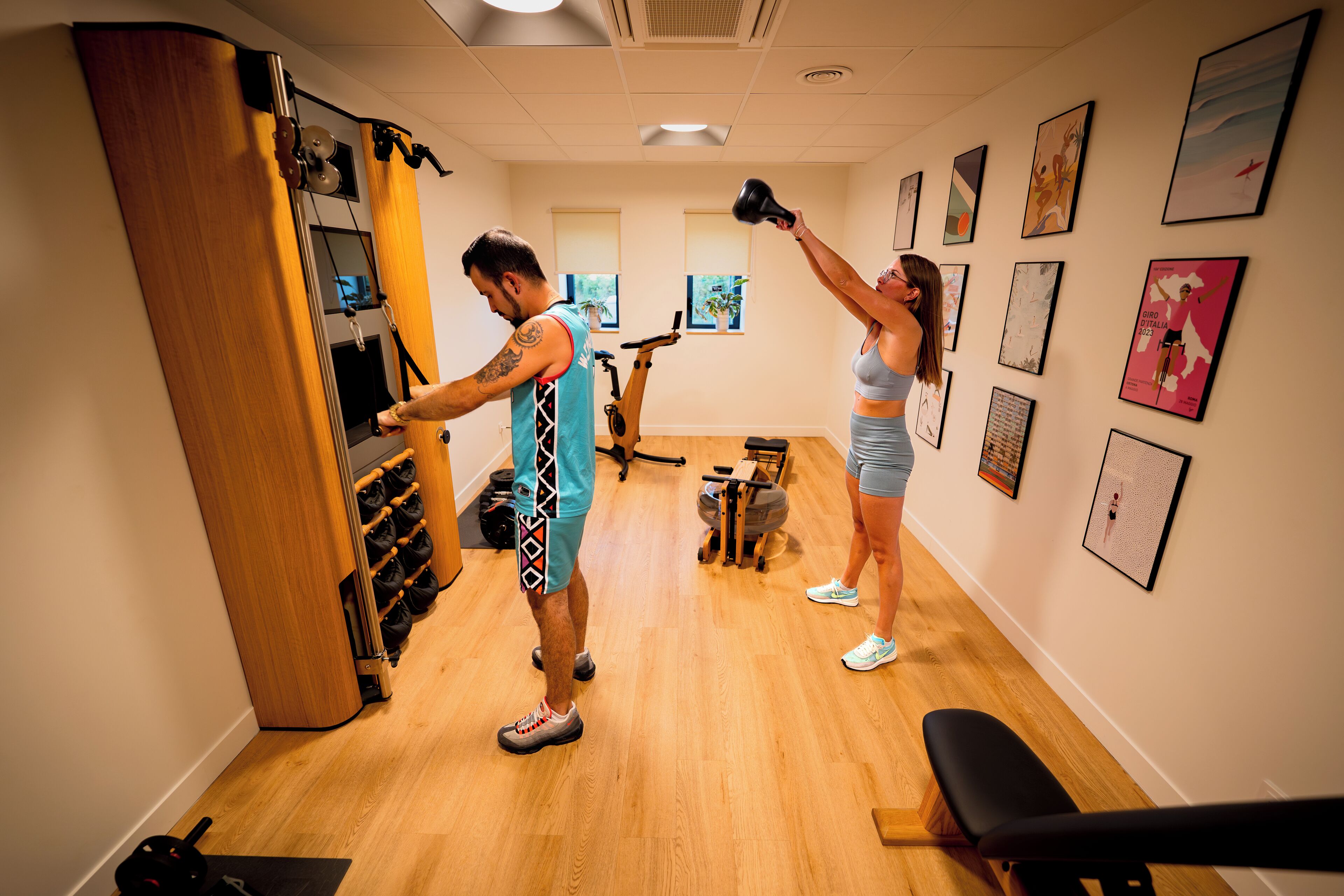A fitness room with exercise equipment, a wall-mounted rack, and a bench.