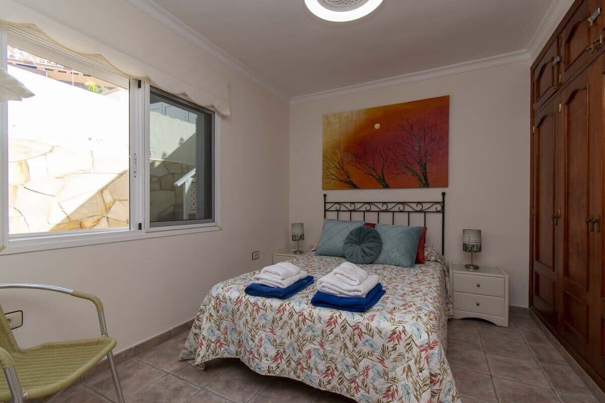 A bedroom with a bed, a window, a painting, and a wardrobe.