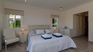 Ein Schlafzimmer mit einem großen Bett, zwei Nachttischen, einem Sessel und einem Kleiderschrank.